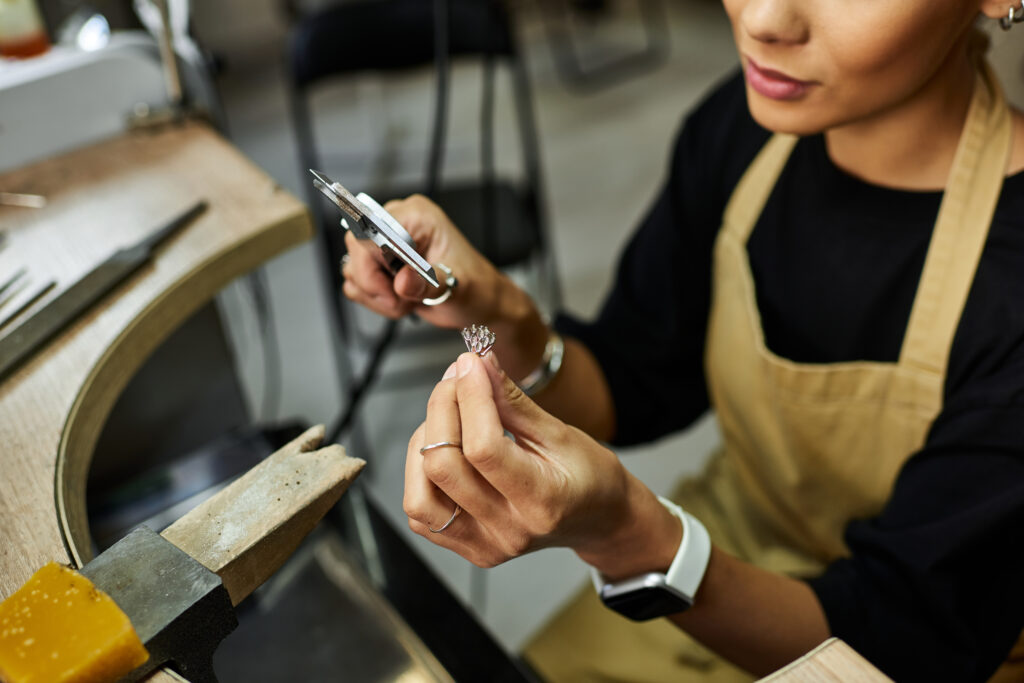 Skilled artisan measuring a custom moissanite ring setting with precision calipers at a jeweler's workbench, highlighting craftsmanship and attention to detail in sustainable jewelry design.